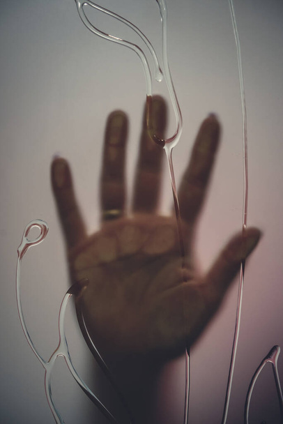 Ανθρώπινο χέρι πίσω από παγωμένο γυαλί πόρτας, κοντά - Φωτογραφία, εικόνα