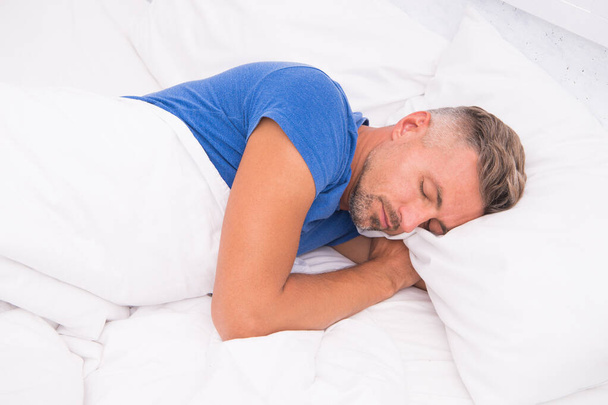 Relaxed man. Promote prevention and management of sleep disorders. World Sleep Day. Benefits of good and healthy sleep. Breathe Easily, Sleep Well. Handsome man in bed. Sleeping guy at home - Foto, afbeelding