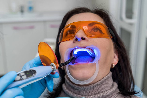 Žena v ochranných brýlích sedí v křesle zubaře - Fotografie, Obrázek