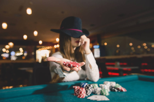 Женщина в шляпе предлагает фишки казино на ладони
 - Фото, изображение