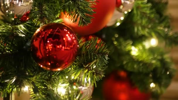 Одяг Фестивально декорованого відкритого різдвяного дерева з яскраво-червоними кульками на розмитому іскристому фоні. Розбиті ліхтарі на сонці, ефект Бокі. Веселого Різдва і щасливих свят. - Кадри, відео