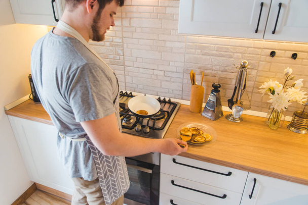 台所でフライパンで揚げる男。料理のコンセプト。家庭生活 - 写真・画像
