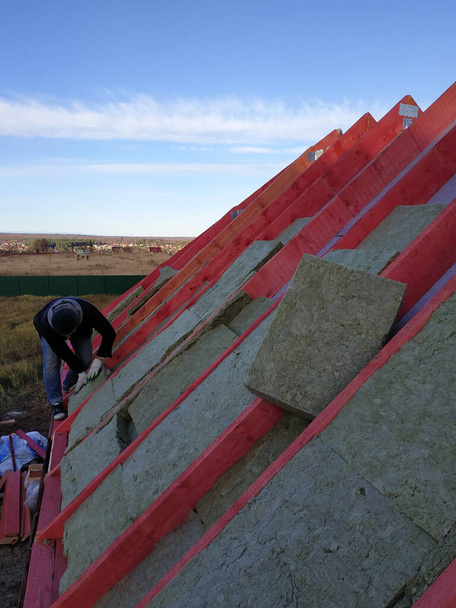 O trabalhador coloca lã mineral no telhado, isolando a casa.2020
 - Foto, Imagem