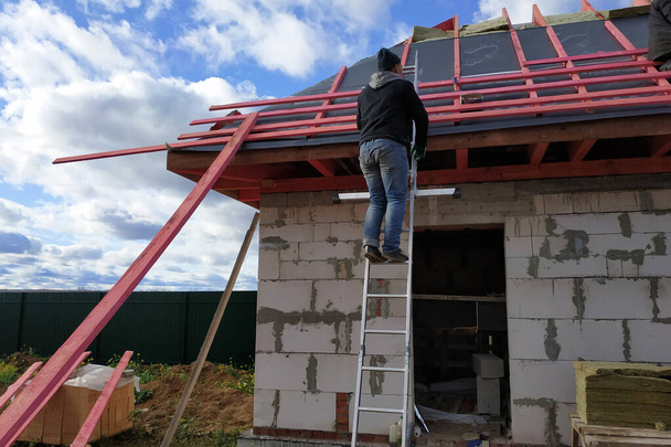 Οι εργαζόμενοι καλύπτουν την οροφή με μονωτικό υλικό, το μονώνουν από το κρύο και το νερό.2020 - Φωτογραφία, εικόνα