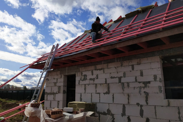 A dolgozók szigetelőanyaggal fedik le a tetőt, szigetelik a hidegtől és a víztől.2020 - Fotó, kép