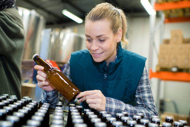 factory worker operating conveyor with beer bottles - Фото, изображение