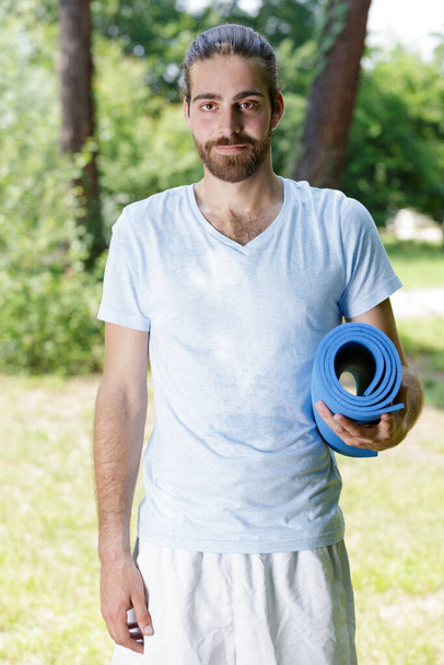 portrait of man holding rolled up yoga mat - Foto, Imagen