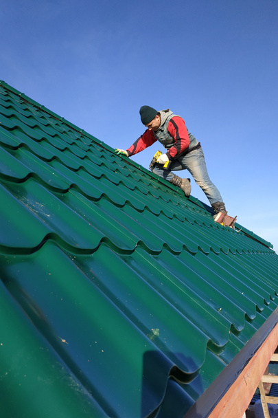A rooftop worker attaches a metal tile to the roof base.2020 - Photo, Image