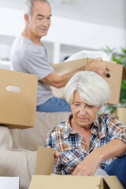 mature couple with moving boxes at new home - Foto, imagen