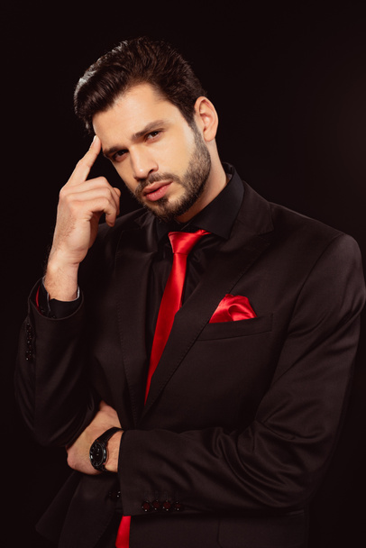 Handsome man in suit and red tie looking at camera isolated on black - Zdjęcie, obraz