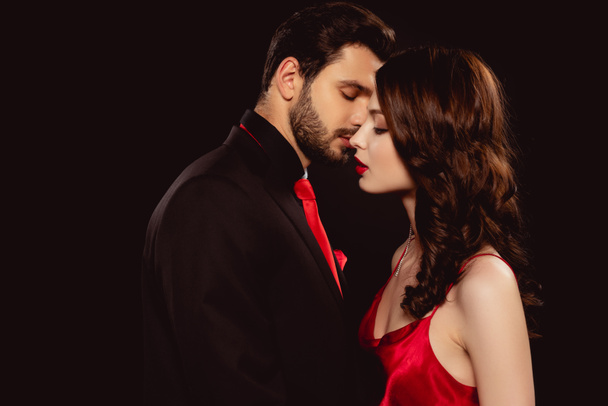 Side view jóképű férfi csók elegáns barátnője elszigetelt fekete - Fotó, kép