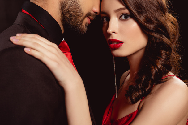 Kırmızı dudaklı güzel bir kız kameraya bakarken siyah bir erkek arkadaşı kucaklıyor. - Fotoğraf, Görsel