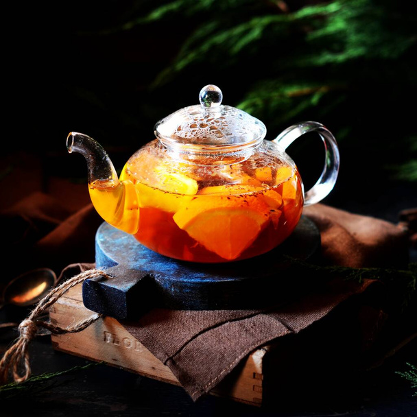 Tè con arancia in una teiera di vetro su uno sfondo scuro. rustico
 - Foto, immagini