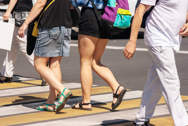 jalankulkijat ylittämässä tietä risteyksessä kaupungin aurinkoisena kesäpäivänä
 - Valokuva, kuva
