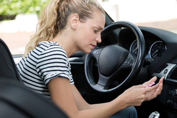 young woman taking pill while driving - Fotoğraf, Görsel