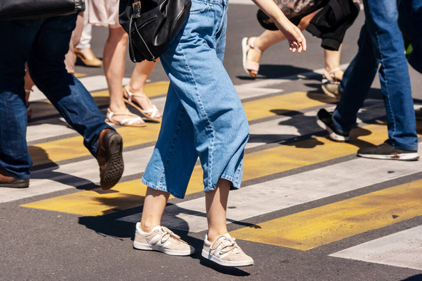 ihmiset ylittävät kadun jalankulkijoiden risteyksessä aurinkoisena kesäpäivänä
 - Valokuva, kuva