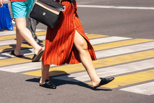 Frau überquert an einem Sommertag die Straße auf einem Fußgängerüberweg in der Stadt. Beine Nahaufnahme - Foto, Bild
