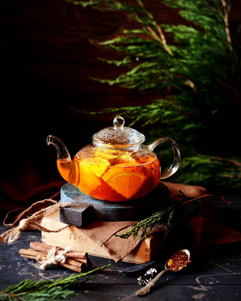 Chá com laranja em um bule de vidro em um fundo escuro. rústico
 - Foto, Imagem