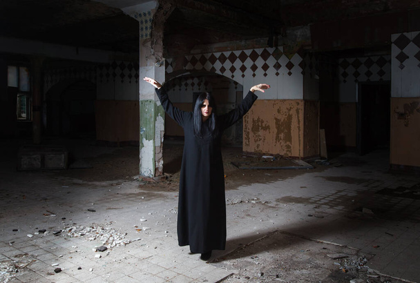 gótikus barna nő felemeli a kezét áll a nagy üres hall sötét komor elhagyatott ház - Fotó, kép