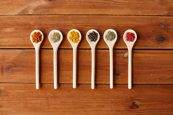 spoons with different spices on wooden table - Фото, изображение
