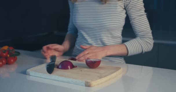 Young woman cutting onion in her kitchen - Záběry, video