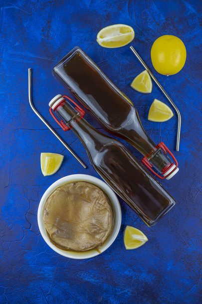 Kombucha Superfood pro biotischen Tee Pilz Getränk in Glasflasche mit Zitrone auf weißblauem Hintergrund. Metallcocktail Strohhalme. flach lag. Kopierraum - Foto, Bild