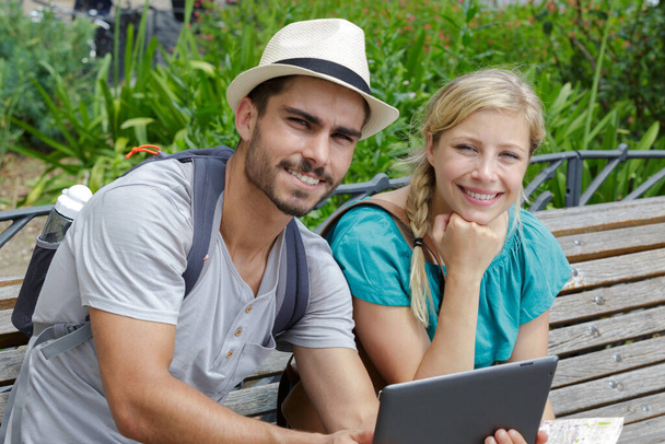 couple on a bench in park using a digital tablet - Zdjęcie, obraz