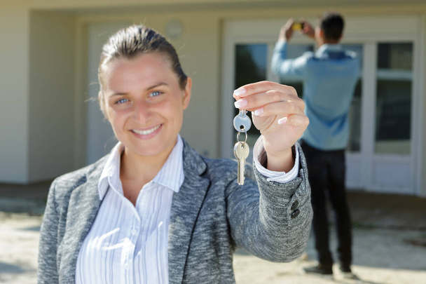 hymyilevä nainen osoittaa avaimet uudesta asunnosta
 - Valokuva, kuva