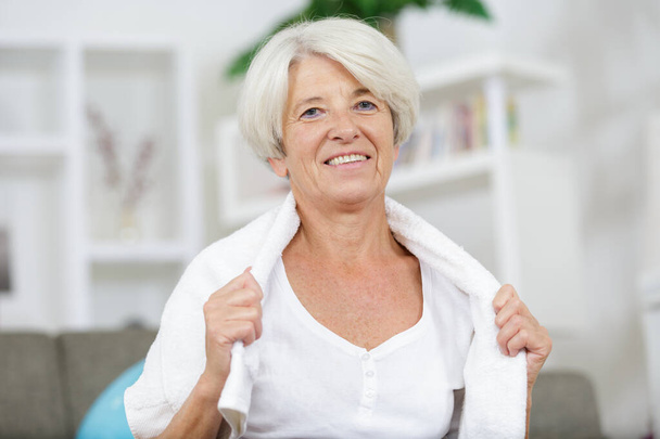 μια ηλικιωμένη γυναίκα με μια πετσέτα γύρω από το λαιμό της χαμογελώντας - Φωτογραφία, εικόνα