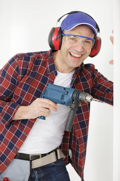 jovial mature man using a drill - Zdjęcie, obraz