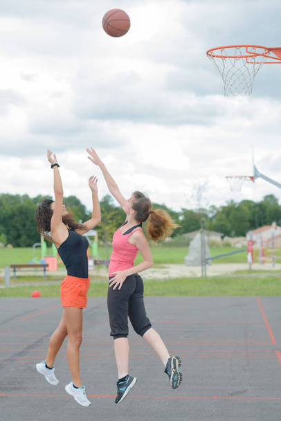 Ladies mid air reaching for basket ball - Фото, зображення