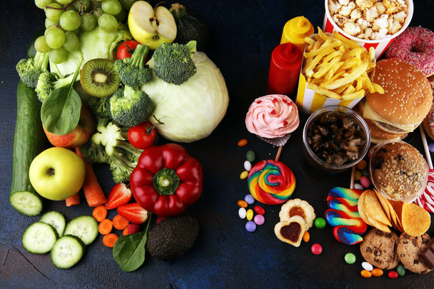 healthy or unhealthy food. Concept photo of healthy and unhealthy food. Fruits and vegetables vs donuts,sweets and burgers on table - Photo, Image