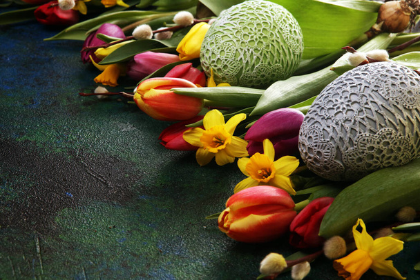 Paaseieren en tulpen en narcissen op rustieke achtergrond. Lente decoratie voor Pasen - Foto, afbeelding