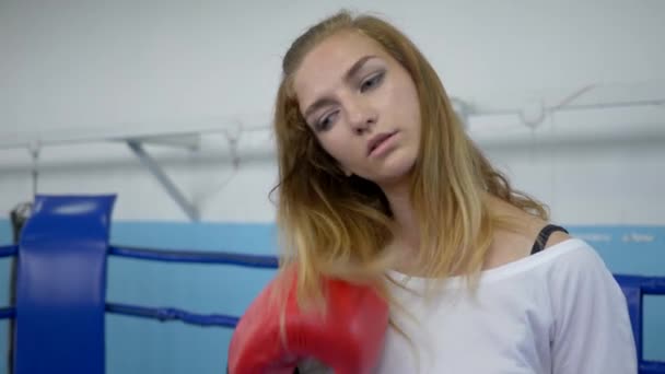 спортивна дівчина на кільці робить точні удари в боксерських рукавичках і дивиться на камеру на тренуваннях
 - Кадри, відео