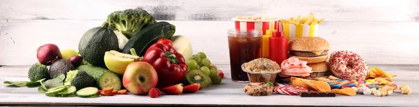 healthy or unhealthy food. Concept photo of healthy and unhealthy food. Fruits and vegetables vs donuts,sweets and burgers on table - Photo, Image
