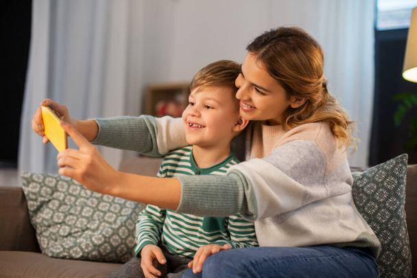 mother and son taking selfie by smartphone at home - Foto, imagen