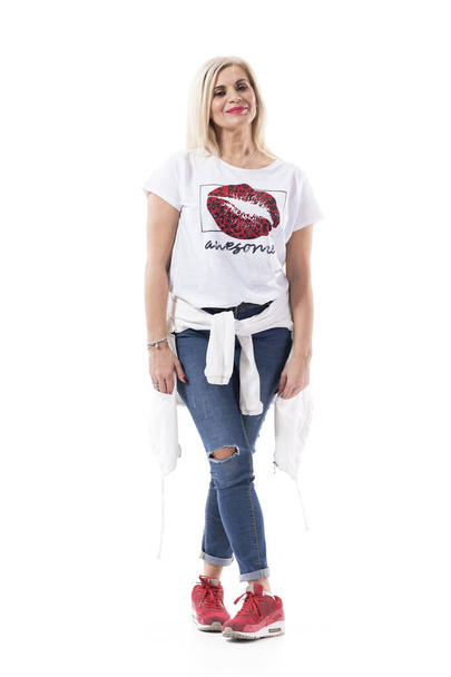 Glücklich bequem entspannte Frau mittleren Alters in Jeans, die mit gesenkten Armen posiert. Volle Körperlänge isoliert auf weißem Hintergrund. - Foto, Bild