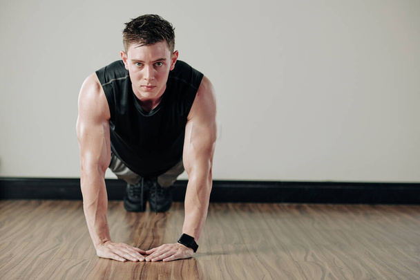 Strong muscular handsome young man doing heart push-ups and looking at camera - Photo, Image