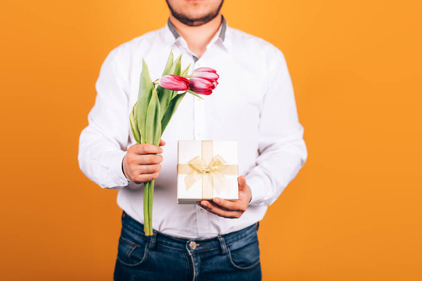 regalo y tulipanes en manos masculinas
 - Foto, imagen