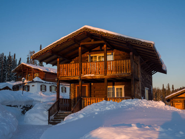 Hotel im alpinen Stil im Skigebiet Gornaja Salanga. Die Sonne geht auf. Schöne Morgenbeleuchtung - Foto, Bild