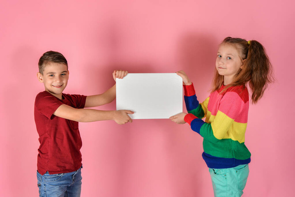 Мальчик с девочкой держит чистый белый плакат с надписью и рекламой
. - Фото, изображение