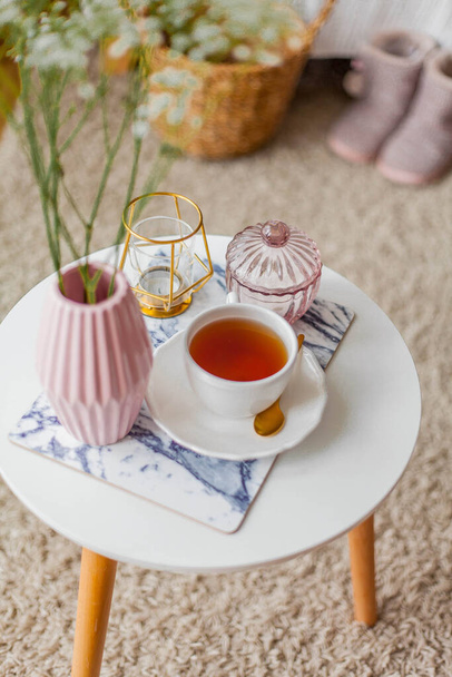 Spring home cozy interior. A bouquet of flowers in a vase, a cup of tea, decor on a coffee table. Mood. - Foto, immagini
