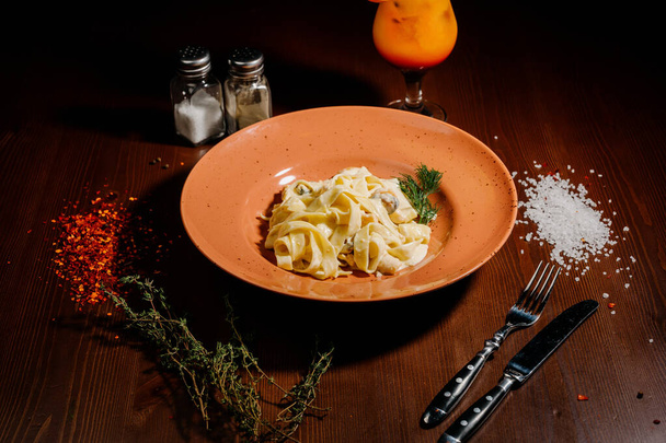 Pasta fettuccine with mushrooms in creamy cheese sauce on a dark wooden background.Top view - Fotó, kép