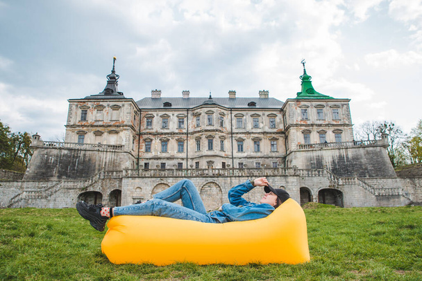 mladá hezká žena ležící na žluté nafukovací matraci před starým hradem. cestovní koncept - Fotografie, Obrázek