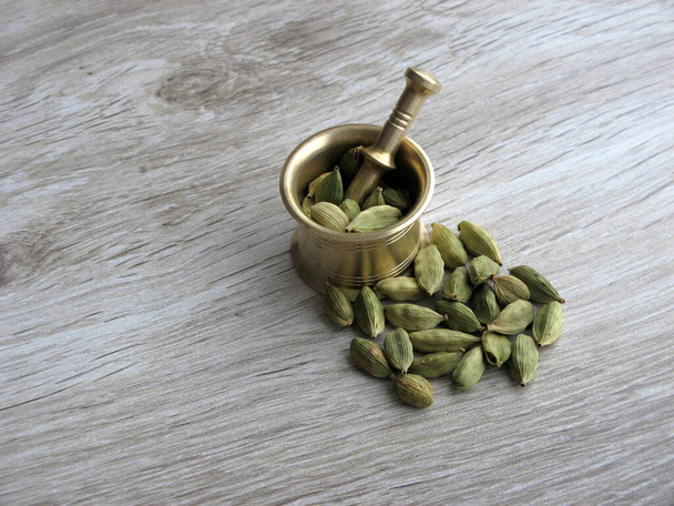 Cardamom pods and mortar on wooden background with space for text. Ayurveda treatments. Traditional treatment. - Photo, Image