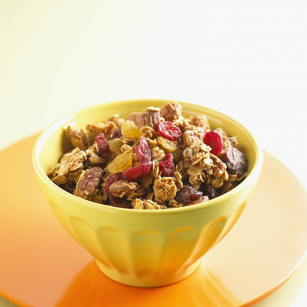 A yellow bowl of Muesli made of nuts and dried fruit on a table - Fotografie, Obrázek