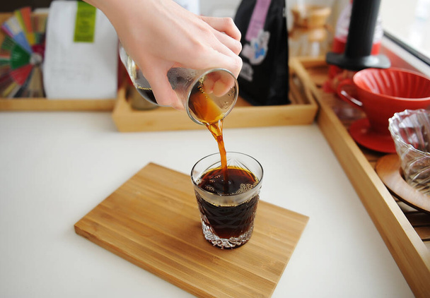 Manuelles Kaffeebrauen Stillleben. Filterkaffee aus Kannen-Karaffe in Kristallglas gießen. Bambusschale vorhanden. Ästhetik der dritten Welle - Foto, Bild