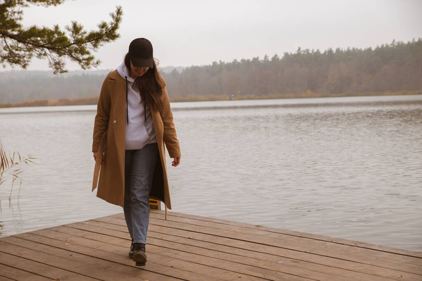 herfst meer seizoen vrouw in jas op houten pier vallen - Foto, afbeelding