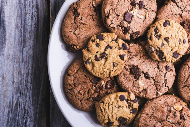 A closeup shot of a lot of chocolate chip cookies in a white plate - Foto, Bild