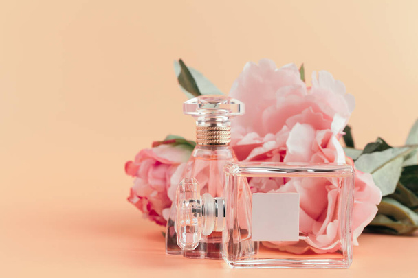 Bottle of perfume with flowers on light cloth - 写真・画像